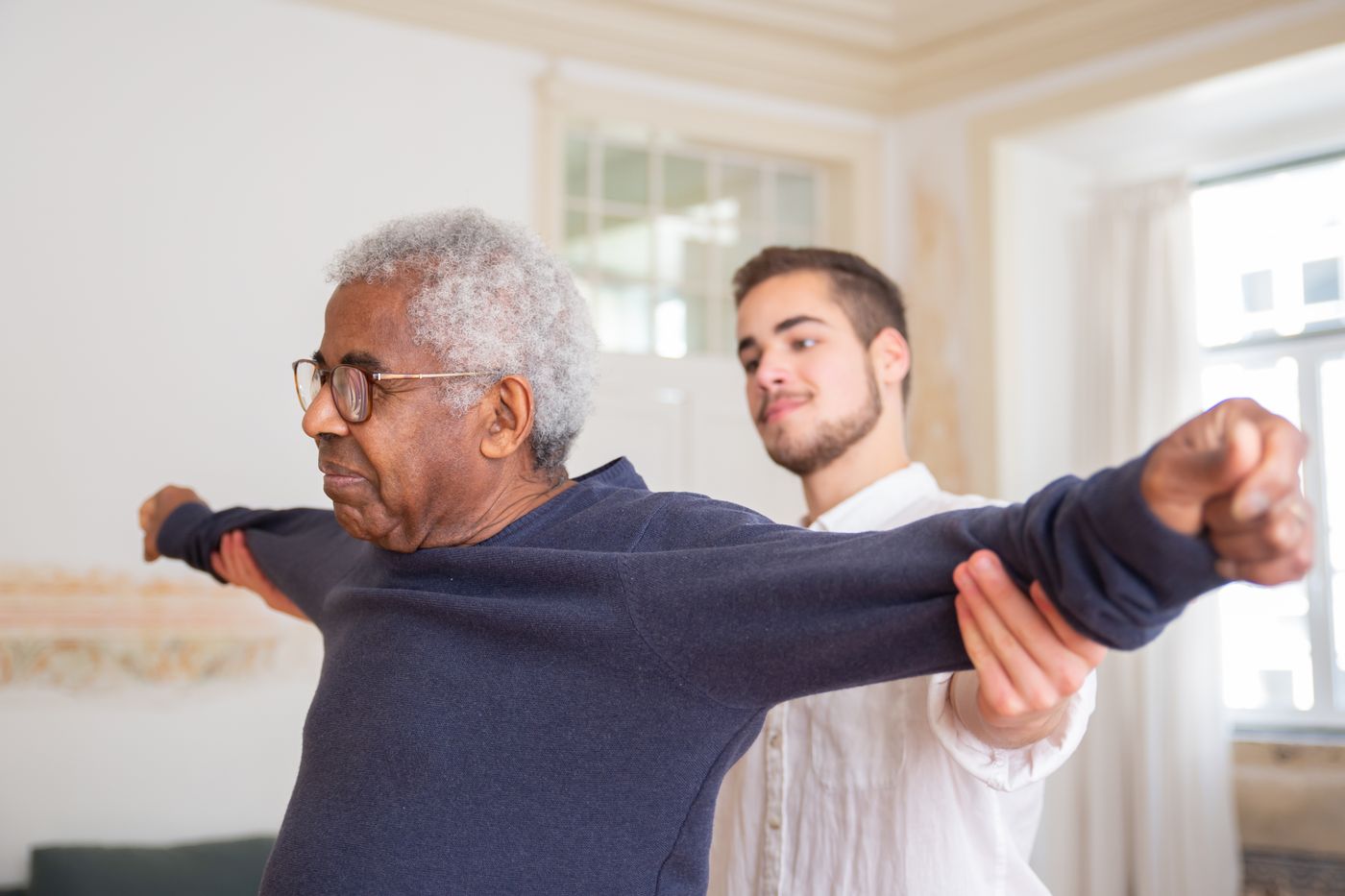 An older man practicing a stretch with a guide