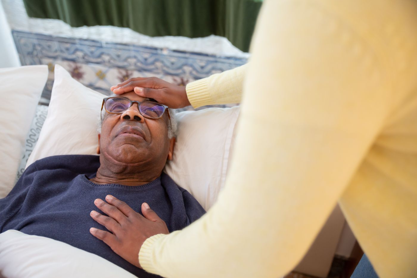 Comfort care beside an older man resting in bed